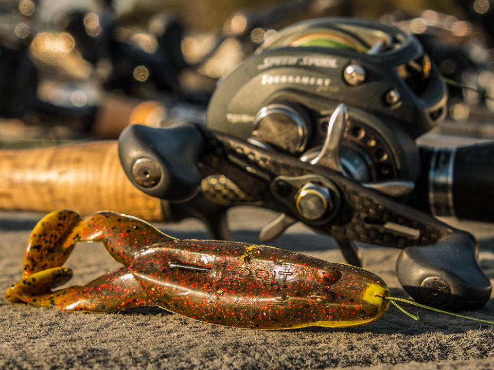 A Culprit Incredi-Frog lure laying on the boat deck in front of a Lews baitcaster